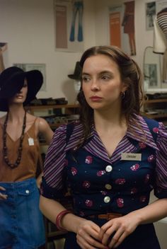 three mannequins wearing hats and dresses in a room filled with clothing items