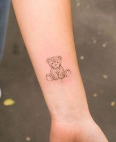 a small teddy bear tattoo on the left inner arm and wrist, is shown in black ink