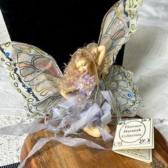 a fairy figurine sitting on top of a wooden table next to a book