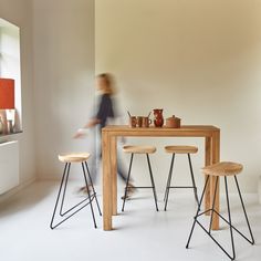 a person walking past a table with stools