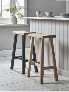 two wooden stools sitting next to each other in front of a kitchen counter top