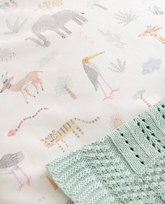 a close up of a blanket on a bed with animals and giraffes