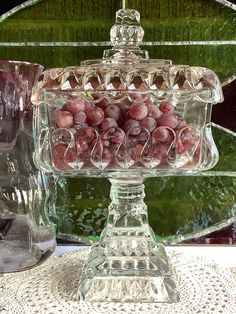 a glass dish filled with grapes on top of a table