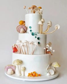 a three tiered white cake with mushrooms and other things on it's side