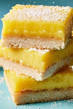 four pieces of lemon bars stacked on top of each other with powdered sugar around them