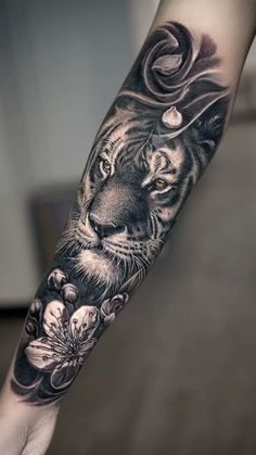 a black and white tiger with flowers on his arm is shown in this tattoo design