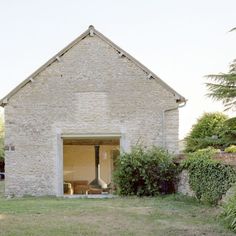 an old brick building sitting in the middle of a field next to trees and bushes