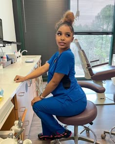 a woman in scrubs is sitting on a chair