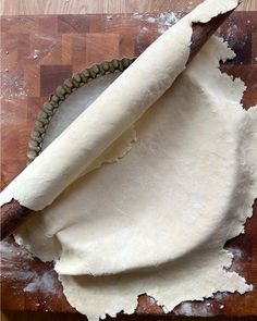 a wooden cutting board topped with uncooked dough and a rolling pin next to it