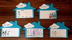 four paper houses with children's drawings on them sitting on top of a wooden table