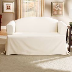 a living room with a white couch covered in a cover next to a coffee table