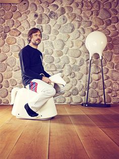 a man sitting on top of a toilet in front of a stone wall and floor