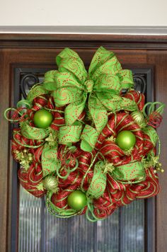 a green and red christmas wreath hanging on a door