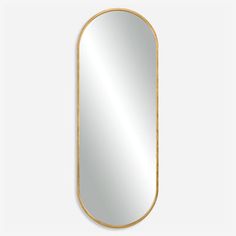 an oval gold framed mirror on a white wall, with the reflection of a person's face in it