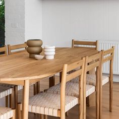 a wooden table with chairs around it and a vase on top of the dining room table