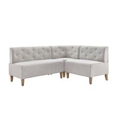 a white sectional couch with tufted backrests and wooden legs on an isolated background