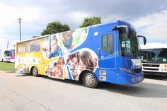 a blue bus with pictures on the side is parked next to other buses in a parking lot