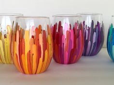 four different colored vases sitting next to each other on a white surface with no one in them