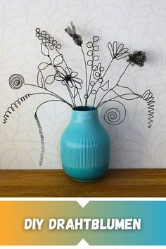 a blue vase filled with lots of flowers on top of a wooden table next to a wall