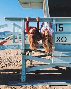 two girls hanging upside down on a lifeguard tower