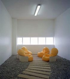 two yellow chairs sitting on top of a carpeted floor in front of a window