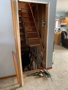 an open door with tools on the floor in front of it and stairs leading up