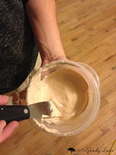 a person is spreading peanut butter into a bowl