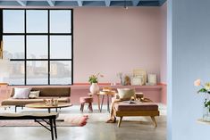 a living room with pink walls and furniture in front of a large window that looks out onto the water