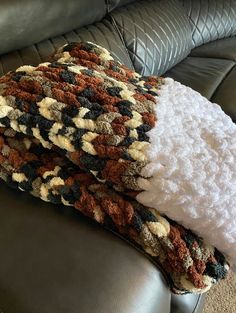 two pillows are sitting on the back of a leather couch, one is covered with white and brown blankets