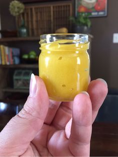 a hand holding a jar filled with yellow liquid