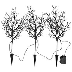 three black trees with no leaves are connected to an electrical outlet and plugged into the ground