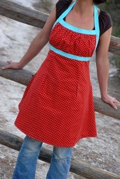 a woman in an apron standing on a wooden fence with her hands out to the side