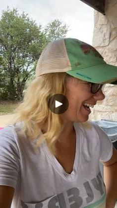 a woman wearing a green hat and smiling at another woman in a white t - shirt