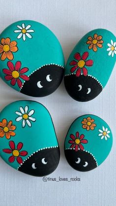 three painted rocks with flowers on them