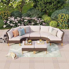 an outdoor living room with furniture and flowers in the backgroung, surrounded by greenery