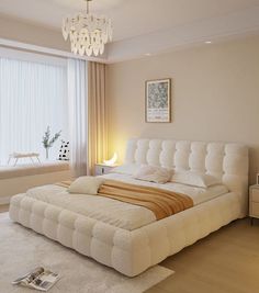 a large white bed sitting in a bedroom under a chandelier next to a window