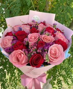 a bouquet of pink and red roses wrapped in paper