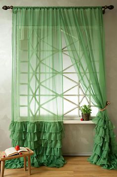 a green curtain with ruffles hanging from it's side in front of a window