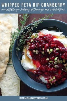 Close up of whipped feta dip with cranberries and pistachio nuts over top next to dippers of homemade rosemary crackers.