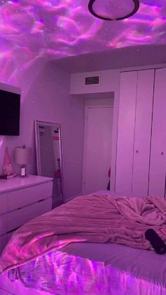 a bedroom with pink and purple lights on the ceiling, white dressers and bed