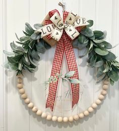 a wreath is hanging on the front door with two wooden beads and a ribbon around it