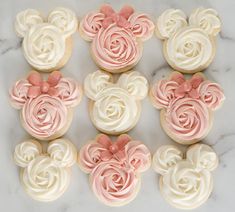 cupcakes with pink and white frosting shaped like mickey mouse heads on a marble surface