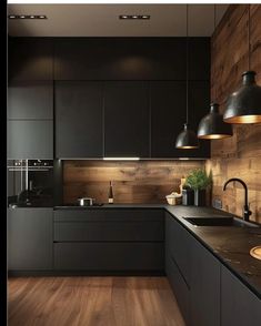 a modern kitchen with black cabinets and wood flooring is pictured in this image, there are three pendant lights hanging over the sink