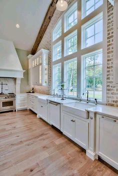 a large kitchen with white cabinets and wood flooring on the walls is pictured in this image