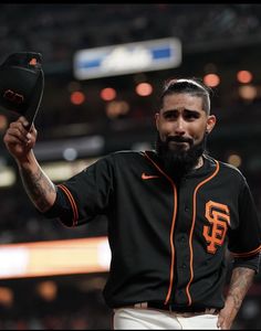 a man with a beard holding up a baseball glove in front of an audience at a game