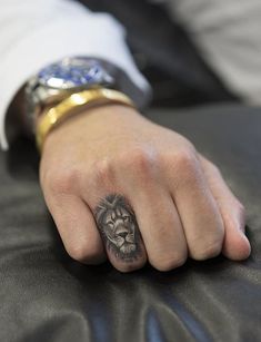 a man with a lion tattoo on his left hand, sitting in a leather chair