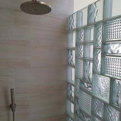 a shower with glass tiles on the wall next to a shower head and faucet