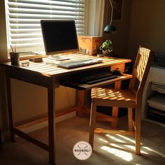 a wooden desk with a computer on top of it next to a window covered in blinds