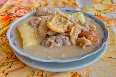 a bowl of food with meat and potatoes in it on top of a table cloth