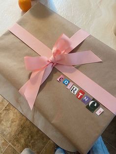 a gift wrapped in brown paper with pink ribbon and the word congratulations written on it